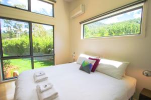 a bedroom with a large bed with two windows at The Base One in Harrietville