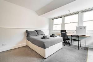 a white bedroom with a bed and a desk and chairs at Finchley Road Studio 13 in London