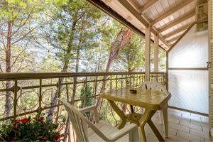 a porch with a wooden table and chairs on a balcony at Alexandros Apartments in Ipsos