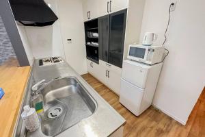 een kleine keuken met een spoelbak en een magnetron bij 万博会場まで直通2駅10分USJ海遊館近い 朝潮橋駅徒歩4分無料駐車場有り最大12名宿泊可能 Wifi ベビー用品充実 in Osaka