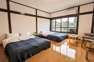 een kamer met 2 bedden, een bank en een raam bij 万博会場まで直通2駅10分USJ海遊館近い 朝潮橋駅徒歩4分無料駐車場有り最大12名宿泊可能 Wifi ベビー用品充実 in Osaka
