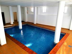 una gran piscina con columnas blancas en una habitación en CASA DIEGO PUERTO BLANQUILLO, en Frigiliana