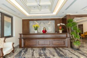 a woman standing behind a reception desk in a lobby at Royal Dương Nội Hotel in Hanoi