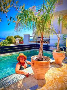 a woman laying in a pool next to two potted trees at Odysseas ART Villa in Póros Kefalonias