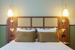 a bedroom with a large bed with two lights on it at voco Paris - Porte de Clichy, an IHG Hotel in Clichy