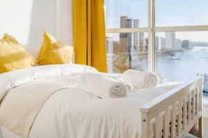 ein weißes Bett mit Handtüchern und einem Fenster in der Unterkunft Riverview 2 Bedroom and 2 Bath Apartment in London