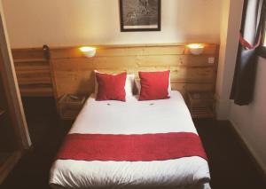 a bedroom with a large bed with red pillows at Hôtel Valentin in Les Deux Alpes