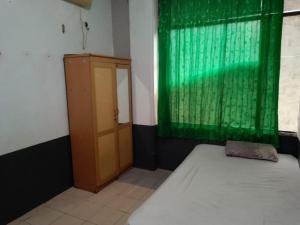 een kamer met een bed en een groen gordijn en een deur bij Penginapan 21 By SPAZIE in Jakarta