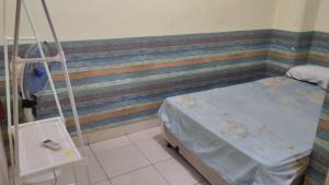 een ziekenhuisbed in een kamer met een gestreepte muur bij Penginapan 21 By SPAZIE in Jakarta