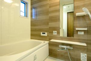 a bathroom with a tub and a mirror at Home n Lounge in Tokyo