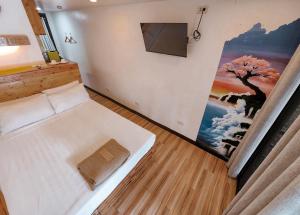 um quarto com uma cama com um quadro na parede em Kaliraya Surf Kamp by Eco Hotel Laguna em Cavinti
