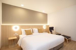 a bedroom with a large white bed and a chair at Diya Hotel Bangkok in Amphoe Phra Khanong +98 photos