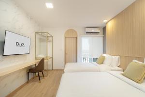 a hotel room with two beds and a desk at Diya Hotel Bangkok in Amphoe Phra Khanong