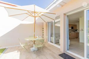 une terrasse avec une table et un parasol dans l'établissement Le Mâconnais Guest House, à Vinzelles