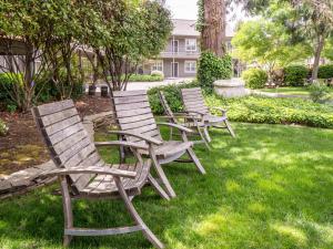 four rocking chairs sitting in the grass in a yard at Wine Country Inn in Jacksonville