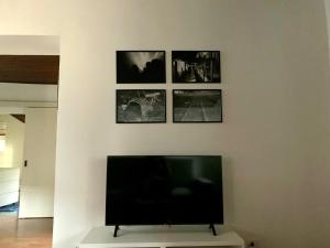 a flat screen tv on a white wall with pictures at Casetta Margherita 4 ospiti- Strategic Position in Bergamo