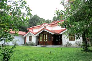 Casa blanca con techo rojo y patio en Villa Kengalle, en Kandy