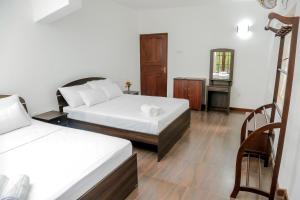 Habitación de hotel con 2 camas y espejo en Villa Kengalle, en Kandy