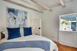 a bedroom with a bed with blue pillows and a painting at Allèe Bleue Wine Estate in Simondium