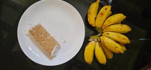 a plate with a piece of cake and a bunch of bananas at LemonTree Homestay & Camping in Kollam
