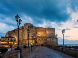 um grande castelo sentado ao lado do oceano ao anoitecer em Casa Don Renato em Nápoles