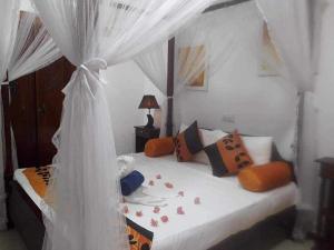 a bedroom with a white canopy bed with flowers on it at Aura Beach Villa in Awariwatta
