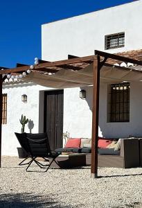 une terrasse avec un lit et une chaise en face d'un bâtiment dans l'établissement Casa Rural “Los Campos”, à Almogía