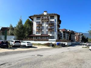 a building with cars parked in a parking lot at Belvedere Holiday Club nice place in Bansko