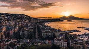 a sunset over a city with a harbor and a mountain at Napoli Suite Station in Naples