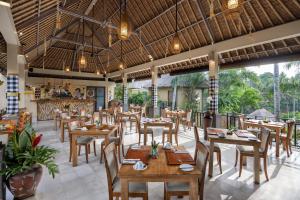 a restaurant with wooden tables and chairs and large windows at The Sankara Resort by Pramana in Ubud