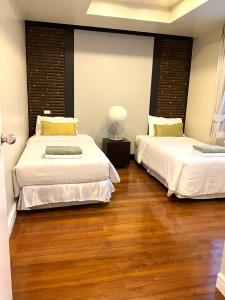 2 camas en una habitación con suelo de madera en Bel Air Cape Panwa Resort Phuket, en Panwa Beach