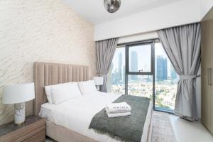 een slaapkamer met een bed en een groot raam bij Nasma Luxury Stays - Burj Royale 2BR Apartment in Downtown With Views in Dubai