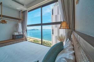 a bedroom with a large window with a view of the ocean at Apec Mandala Mũi Né Condotel By Vũ in Mui Ne