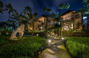 ウブドにあるThe Sankara Resort by Pramanaの芝生の灯りを持つ夜の家