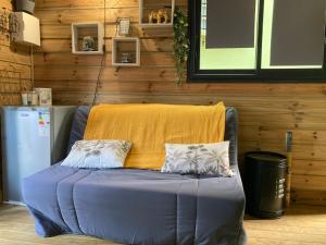 a blue couch with two pillows on it in a room at Tiny house bois cosy « Halte là » in La Possession