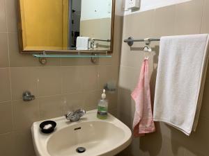 a bathroom with a sink and a mirror and towels at The Sheltuh : Closer to everything Colombo in Manning Town