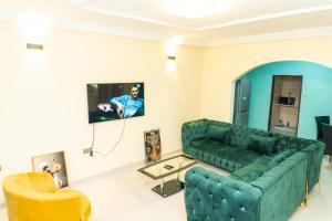 a living room with a green couch and a tv at Vyemma Residence in Limbe