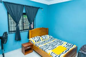 a blue bedroom with a bed and a window at Vyemma Residence in Limbe