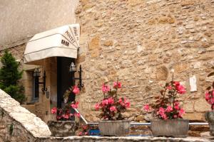 a stone building with three potted plants with pink flowers at Hostellerie Maleville, logis hôtel Pontet in Beynac-et-Cazenac