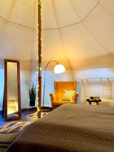 a bedroom in a tent with a bed and a chair at Lotus Glamping in Tiszalök