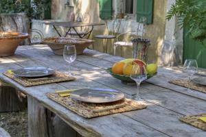een houten tafel met borden en glazen en een fruitschaal bij Le Mas des Anges in Cabannes