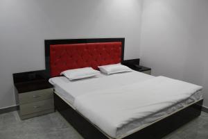 uma cama com uma cabeceira vermelha e duas almofadas em The Dharams Hotel em Lucknow