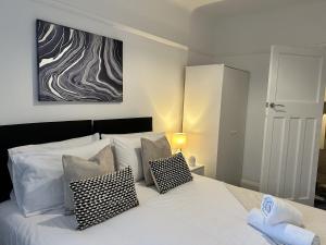 een slaapkamer met een wit bed met kussens en een schilderij bij Charming Apartment Near Broad Green Hospital in Liverpool
