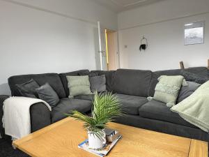 a living room with a black couch and a table at Charming Apartment Near Broad Green Hospital in Liverpool