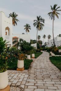 un chemin en pierre en face d'un bâtiment avec des palmiers dans l'établissement LUX Marijani Zanzibar, à Pwani Mchangani