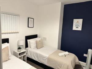 a bedroom with two beds and a blue wall at Charming Apartment Near Broad Green Hospital in Liverpool