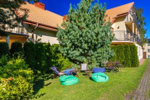 a yard with a house with a tree and some chairs at Willa Chantal in Jastrzębia Góra