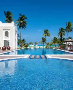 une grande piscine avec des palmiers en arrière-plan dans l'établissement LUX Marijani Zanzibar, à Pwani Mchangani
