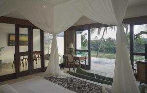 1 dormitorio con cama y vistas a un patio en Motama Villa en Ubud