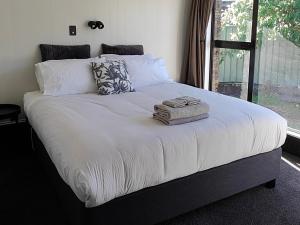a large bed with white sheets and a window at Holiday retreat in the heart of old Cromwell! in Cromwell